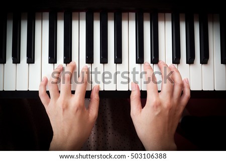 Closeup woman's hand playing piano. Favorite classical music. Top view with dark vignette.