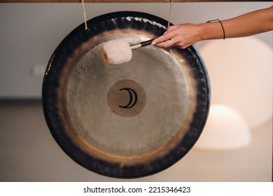 Close-up of a woman's hand pounding a gong with a hammer. Gong and hand beater for gong. - Shutterstock ID 2215346423