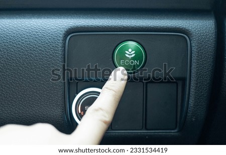 Close-up woman's hand is pressing the fuel economy  or ECO button for the vehicle's fuel economy. Energy-saving driving mode. Energy saving concept. Green eco drive. eco mode to save the environment.