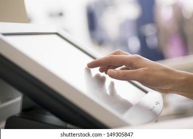 Closeup of woman's hand touching screen of cash register in store
