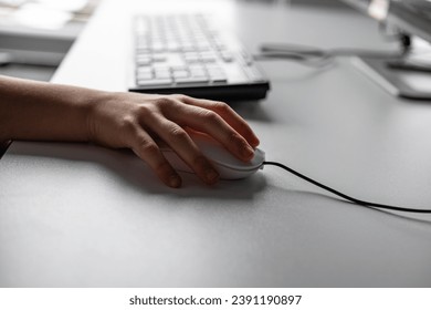 Close-up of a woman's hand using a mouse on a desk