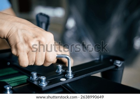 Close-up of a woman's hand using a tool to tighten a nut