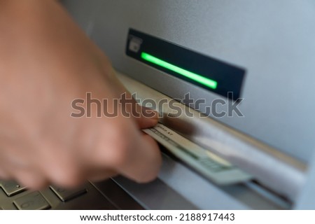 Close-up of a woman's hand withdrawing money from an ATM. Selective focus