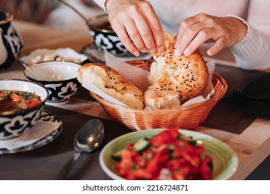 Close-up of woman's hands breaking bread. Female hands holding homemade natural fresh bread with a Golden crust. Asian uzbek traditional bread - Shutterstock ID 2216724871