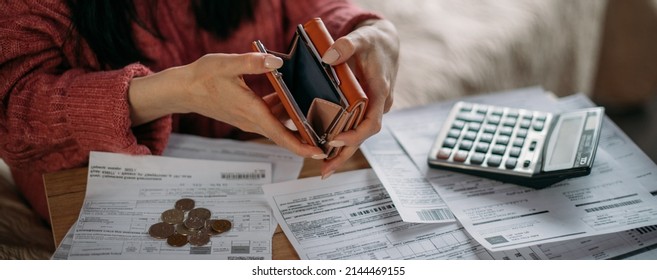 Close-up of woman's hands with empty wallet and utility bills. The concept of rising prices for heating, gas, electricity. Many utility bills, coins and hands in a warm sweater holding an open wallet - Shutterstock ID 2144469155