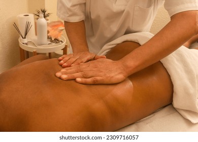 Close-up of a woman's hands expertly applying pressure to a brunette woman's back during a therapeutic massage