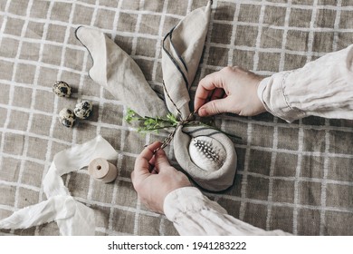 Closeup of womans hands folding napkins. Easter decorative table setting. Spring still life with  quail and hen eggs. Beige linen table cloth background. Flat lay, top view. Craft, home decor concept. - Powered by Shutterstock