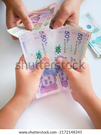 close-up of a woman's hands holding 50,000 Colombian peso banknotes while she negotiates