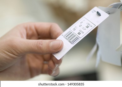Closeup Of Woman's Hands Holding Clothes Tag In Store