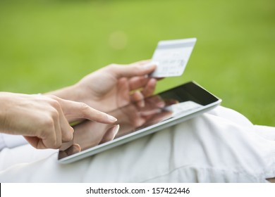 Close-up woman's hands holding a credit card and using tablet pc, online shopping, outdoor