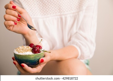 Closeup Of Woman's Hands Holding A Cup With Organic Yogurt With Oats And Cherries.  Breakfast Or Snack. Healthy Eating And Lifestyle Concept.