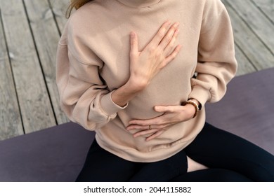 Close-up of a woman's hands on her chest while doing breathing exercises
