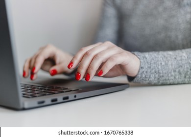 Closeup Of Woman's Hands With Red Nails On The Grey Laptop Keyboard. Young Businesswoman Working In An Office On A Computer. Business, Industry And Job Concept