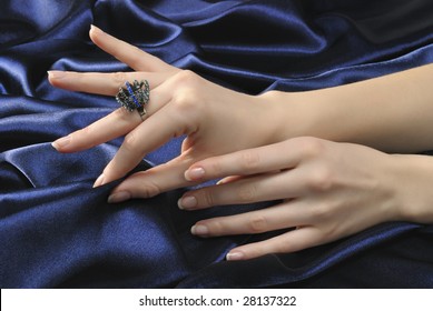 Close-up woman's hands with ring on silky blue background - Powered by Shutterstock