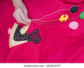 Closeup Of A Woman's Hands Sewing Applique Work Making Doll And Balloon With Chain Stich In Baby’s Quilt Or Bed Sheet. Concept Of Self Employment Woman And Female Entrepreneurs In India.