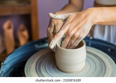 Close-up of a woman's hands shaping a ceramic pot on the lathe - Shutterstock ID 2105876189