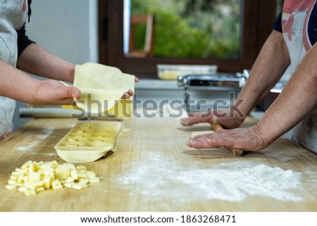 Close-up of woman's hands working the dough to prepare cheese ravioli. Traditional Sardinian cuisine.