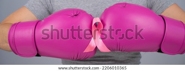Close-up of\
women\'s boxing gloves and pink ribbon.\
