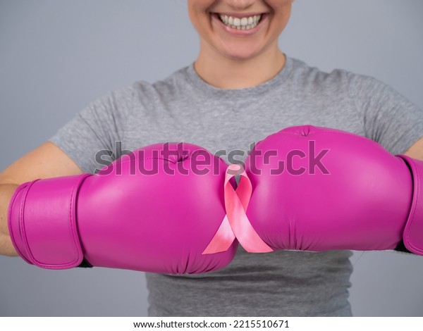 Close-up of\
women\'s boxing gloves and pink ribbon.\
