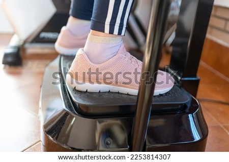 Close-up of women's feet on a vibrating gymnastics machine for sports at home.