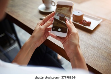 Closeup of women's hands making photo of sweet dessert on mobile phone while sitting in comfortable restaurant, female taking pictures with cell phone camera of delicious pastry during rest in cafe - Powered by Shutterstock