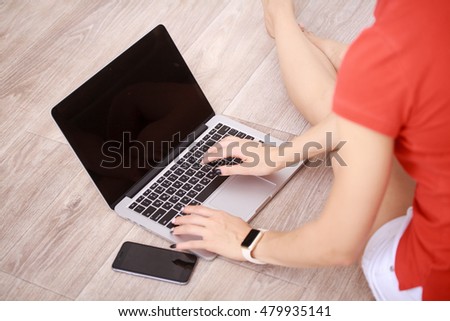 Closeup of women's hands using mobile phone and laptop computer, female keyboarding on net-book