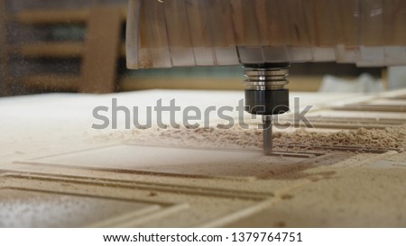 Closeup of wood milling on modern automatic woodworking machine with CNC. furniture production. Cuts curly pieces from plywood sheet.