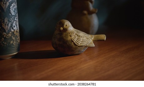 Closeup wooden bird standing on table top indoors. Decorative animal sculpture on chest of drawers in stylish interior. Wood carving figure for home decoration. 