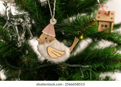 Close-up of wooden bird-shaped Christmas ornament hanging on green pine tree branch, surrounded by soft festive lights. Concept of natural holiday decor, rustic ornaments, and seasonal charm.  - Powered by Shutterstock