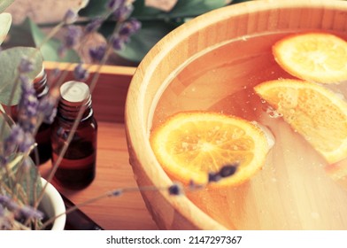 Close-up Wooden Bowl With Fresh Orange Slices Essential Oil, Citrus Scent. Home Aromatherapy Spa Beauty Treatment Set, Herbal Citrus Tincture Mix, Soft Light.
