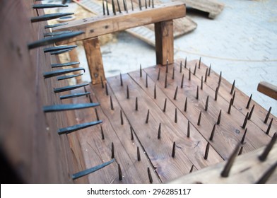 Closeup of a wooden chair medieval torture with nails in the back, seat and armrests.