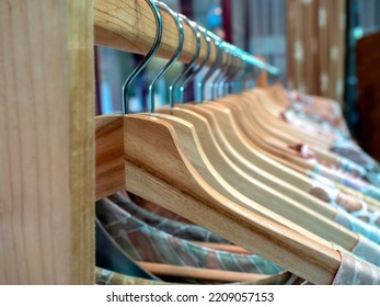 Close-up Wooden Clothes Hangers With Colorful Shirts Hanging On A Wood Cloth Rack In Asian Style Fashion Shop Store.