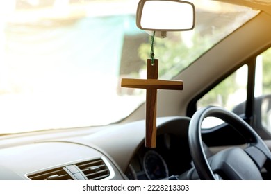 Closeup wooden crucifix hang  in  front steering wheel and console of the car. Concept, talisman,amulet to prevent accidents. Belief, faith,holy  in god to protect when driving.                      