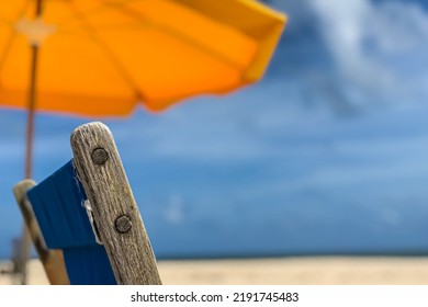 Closeup Of Wooden Deck Chair And Yellow Beach Umbrella Convey A Tranquil South Florida Beach Scene.