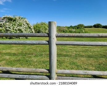 A Closeup Of A Wooden Fence Post Outside Of A Field.