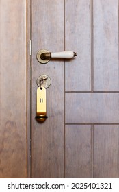 Close-up Of A Wooden Hotel Door With A Golden, Vintage Handle And The Key In The Key Hole.