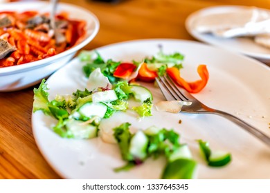 Closeup Of Wooden Table With Messy Half Eaten Green Vegetable Salad And Plate Fork Background