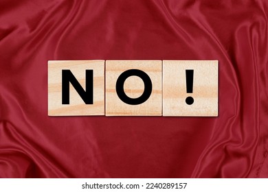 Closeup of wooden tiles spelling out NO! against a charming red silk background. - Shutterstock ID 2240289157