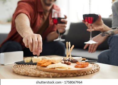 Close-up of wooden tray with different kinds of cheese on the table with couple drinking wine in the background