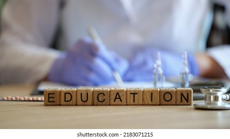 Close-up Of Word Education Collected Of Wooden Blocks In Raw. Doctor In Medical Uniform Writing Information. Medical Education, Training Or Seminar Concept