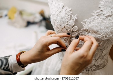 Close-up of work process of a fashion designer at her studio. Hand sewing bridal gown / dress process. Pin lace to dress on a mannequin. 
