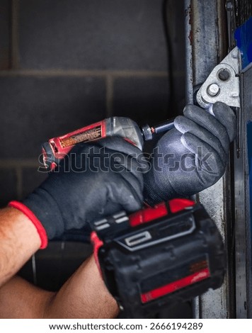 Close-up of a worker attaching rollers to the metal tracks of a garage door during installation or repair.	