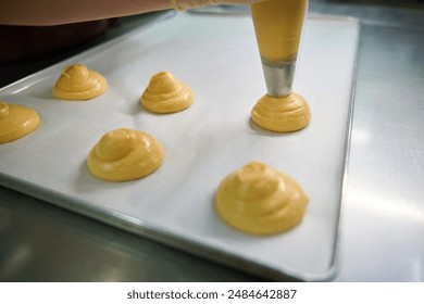 Close-up worker of bakery pipping out choux dough from pastry bag - Powered by Shutterstock