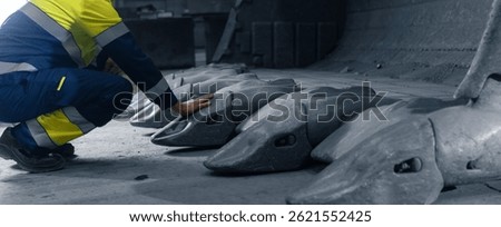 Close-up Worker engineer touches excavator bucket tooth, maintenance of mining truck. Concept industrial machines equipment and people.
