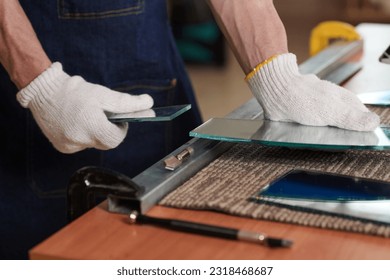 Close-up of worker in gloves making shapes from pieces of glass with special work tool at table - Powered by Shutterstock