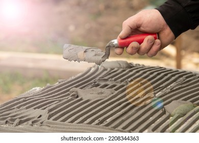 Close-up Of Worker Hand, With Trowel Applying Glue On White Rigid Polyurethane Foam Sheet For House Insulation.