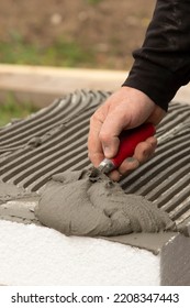 Close-up Of Worker Hand, With Trowel Applying Glue On White Rigid Polyurethane Foam Sheet For House Insulation.