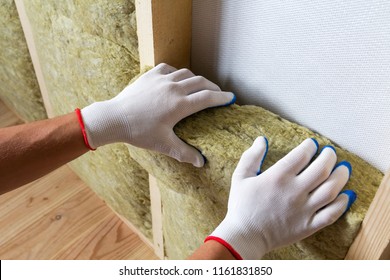 Close-up of worker hands in white gloves insulating rock wool insulation staff in wooden frame for future walls for cold barrier. Comfortable warm home, economy, construction and renovation concept.