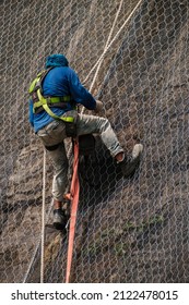 Closeup Of A Worker At Heights With No Safety Helmet Is Working And Fixing Landslide Safety Net