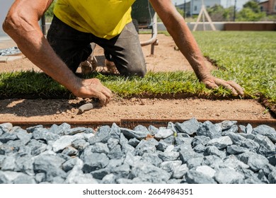 Close-up of worker manually installing turf with knife near a gravel path. Perfect for themes on landscaping, outdoor renovation, and manual craftsmanship - Powered by Shutterstock - Get 15% off with code: PIKWIZARD15